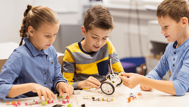 Zwei Mädchen und eine Junge bauen ein Spielzeug zusammen